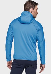 Blauer sportlicher Hoodie mit einem strukturierten, gerippten Design. Verfügt über eine enganliegende Kapuze und lange Ärmel. Kombiniert mit dunklen Sporthosen.