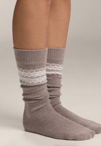 Pletené členkové ponožky v jemnej sivej farbe s preloženým rebrovaným lemom a bielym dekoratívnym vzorom v strede lemu. Textúrovaný dizajn látky.