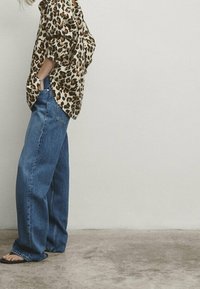 Oversized bluse med leopardmønster og korte ærmer, kombineret med brede blå denim jeans. Sættet har en afslappet pasform og blødt stof.