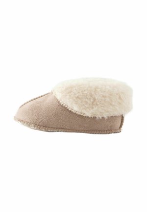 Chausson en beige doux avec un revers en fausse fourrure crème, extérieur en daim moelleux, bout arrondi et détails piqués le long de la semelle.