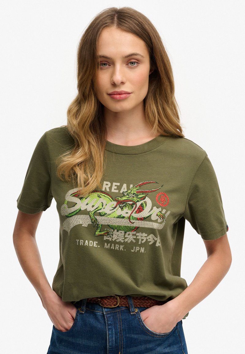 Olijfgroene t-shirt gemaakt van katoen, met een gestructureerde drakenafbeelding in rood en groen, met "Superdry" in vetgedrukte letters.