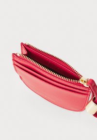 Red textured leather cardholder with gold-tone zipper and hardware. Features multiple compartments for cards and cash. Compact design.