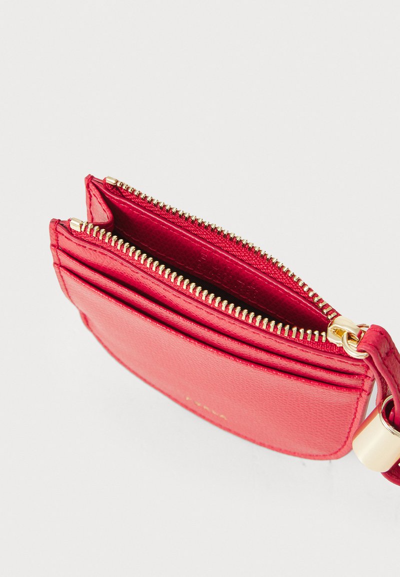Red textured leather cardholder with gold-tone zipper and hardware. Features multiple compartments for cards and cash. Compact design.