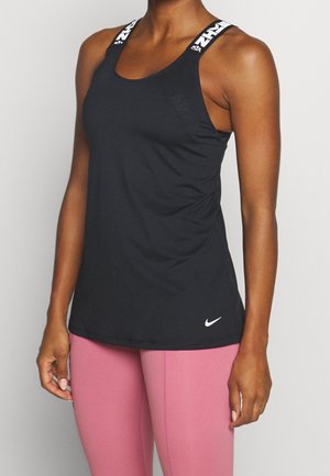 Femme portant un débardeur noir Nike avec des bretelles marquées et des leggings roses, debout, les bras détendus le long du corps.