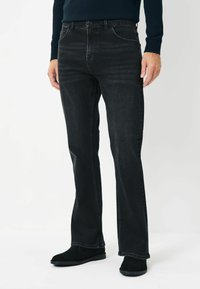 Mustad denim püksid sirge lõikega, peene kulumisega, viie taskuga ja õmblusdetailidega, kombineeritud mustade sametist chelsea saapadega.