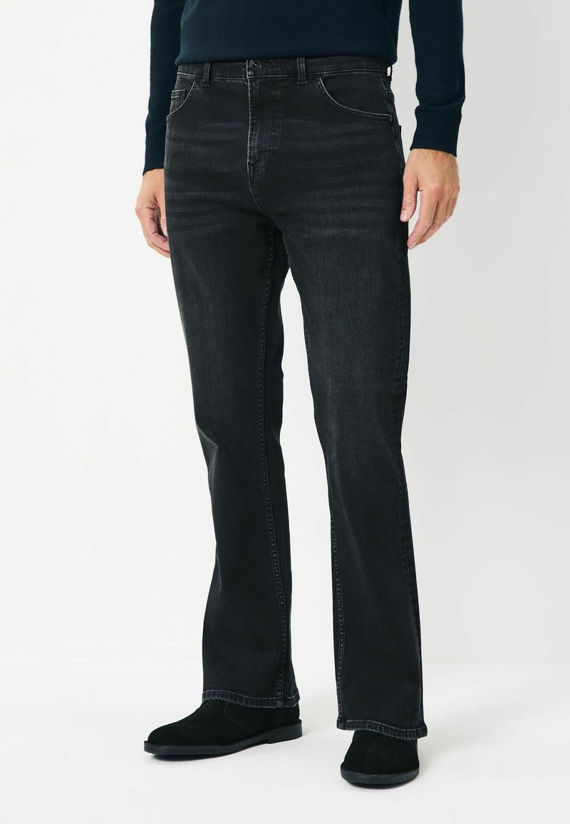 Mustad denim püksid sirge lõikega, peene kulumisega, viie taskuga ja õmblusdetailidega, kombineeritud mustade sametist chelsea saapadega.