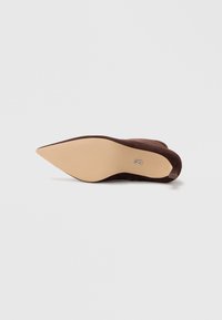 Zapato de tacón alto de ante marrón con punta afilada y suela lisa color marrón claro. Presenta un logotipo sutil en la zona del talón.