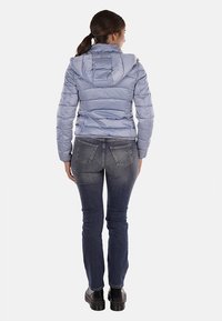 Giacca puffa blu chiaro con cappuccio, design trapuntato orizzontale, abbinata a jeans in denim scuro e stivaletti neri con plateau.