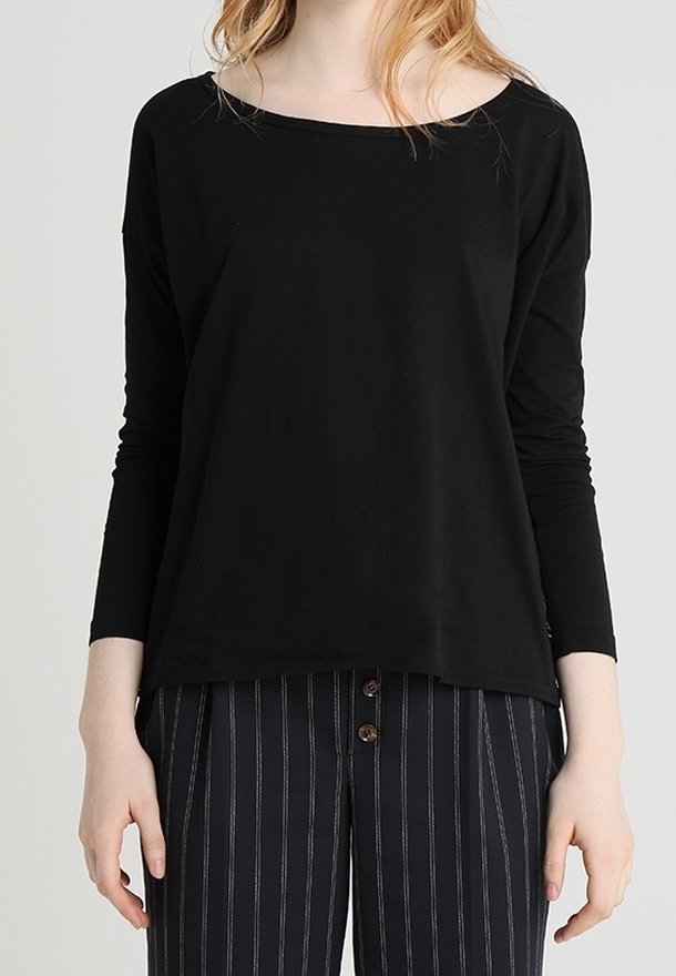 Haut noir à manches longues avec un large col, fabriqué en tissu doux, associé à un pantalon rayé bleu marine et blanc avec des accents de boutons.