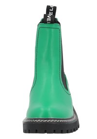 Botas de tobillo de cuero verde con paneles laterales elásticos negros, costuras blancas y una suela negra robusta. Cuentan con una lengüeta para ponerlas con facilidad.