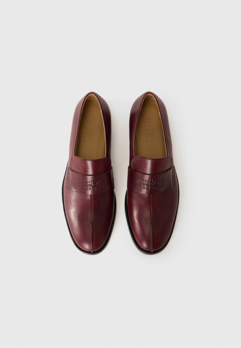 Par av vinröda läder slip-on loafers med svarta sulor, med embossad logotyp och nummerserie-design på de övre remmarna.