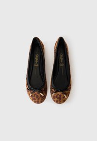 Des ballerines à imprimé léopard avec une bordure noire, présentant un petit nœud à l'avant et une doublure intérieure lisse.