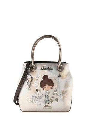 Handtasche mit metallischen Griffen, braunem Riemen, Illustration eines Cartoon-Mädchens und dem Text „In love with knowledge“ auf beigem Hintergrund.