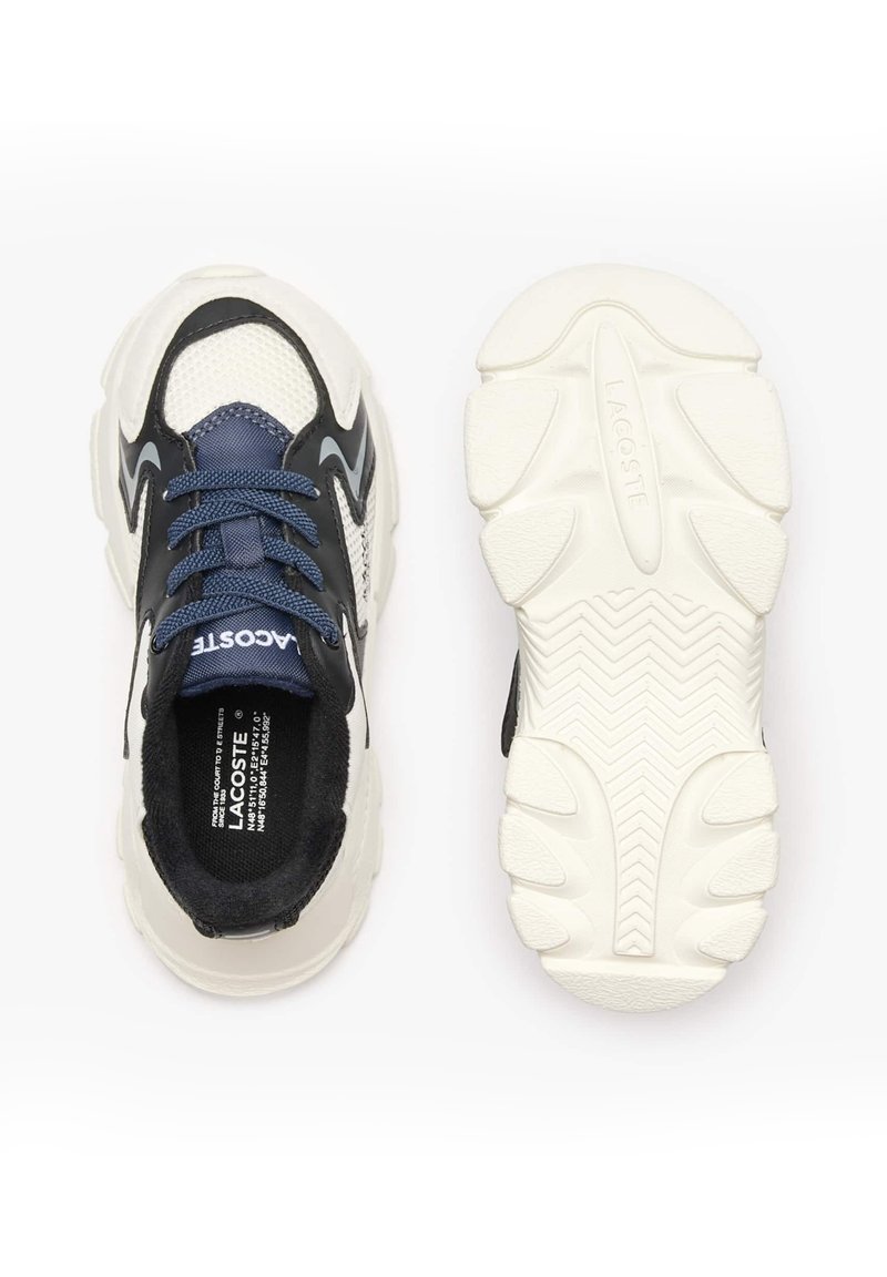 Baskets noires et blanches avec une tige en mesh, lacets bleus et une semelle texturée présentant un motif en vagues. Logo Lacoste sur la languette.