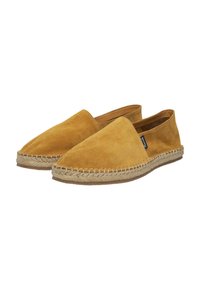 Zapatos slip-on de ante en un color amarillo mostaza con una suela de yute trenzada y detalles trenzados a lo largo del borde. Textura suave en toda la superficie.