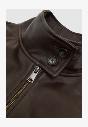 Guler de geacă din piele maro cu textură netedă. Prezintă un fermoar argintiu și două nasturi închiși la culoare aproape de gât. Detalii de design sofisticate.