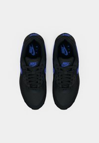 Nike Air sneakers met een zwarte bovenkant, blauwe accenten en een gestructureerde stof. Voorzien van veters en demping in de zool voor comfort.