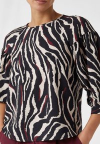 Lässiges Oberteil mit einem schwarz, creme und burgunderfarbenen Zebra-Streifen-Muster, rundem Ausschnitt und gerafften kurzen Ärmeln aus strukturiertem Stoff.