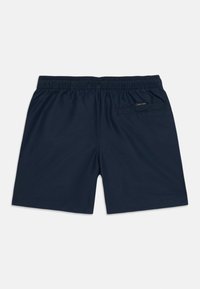 Shorts de bain bleu marine avec taille élastique, poche arrière unique et étiquette Calvin Klein. Tissu lisse et léger, coupe à mi-genoux.