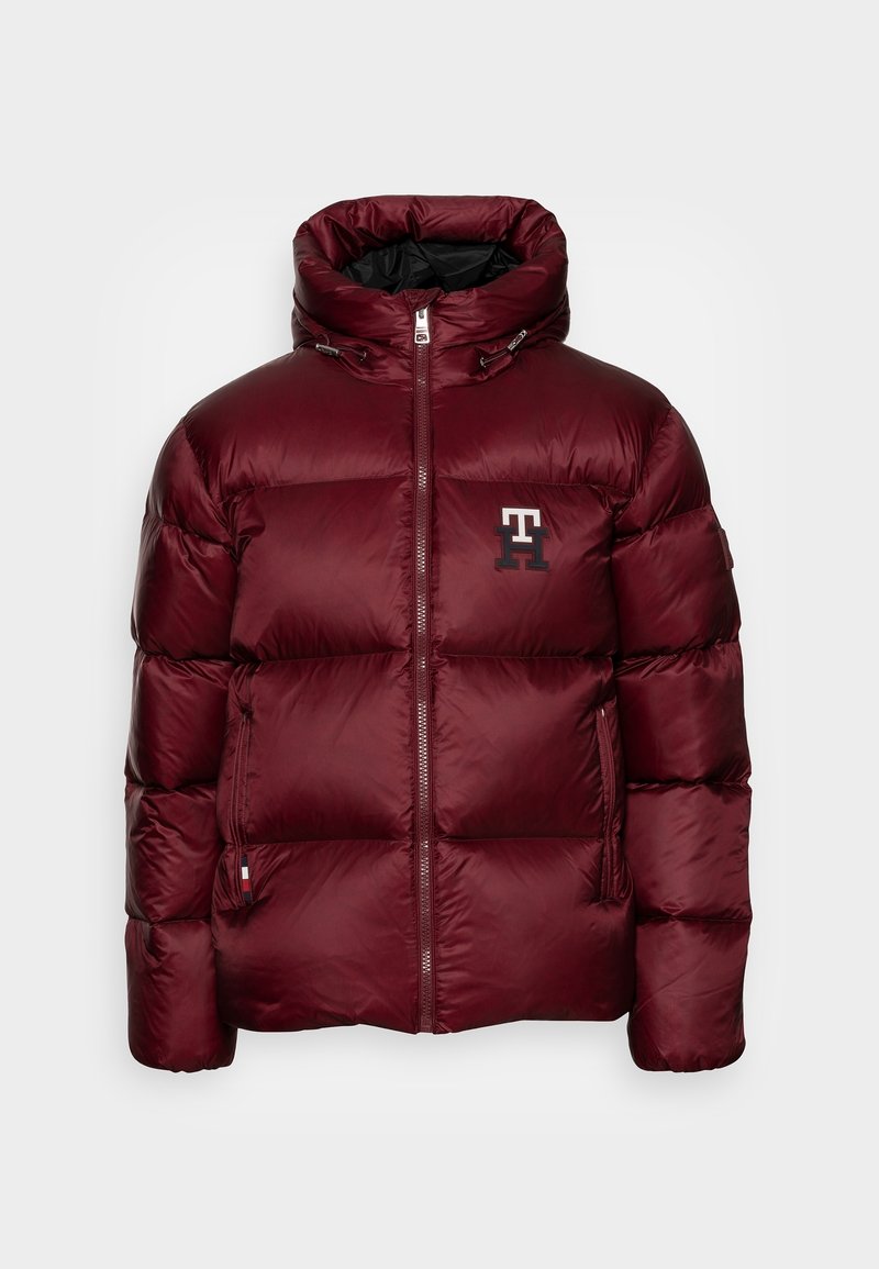 Chaqueta acolchada burdeos con cuello alto, cierre de cremallera y cordones elásticos. Presenta un logo en el pecho y un bolsillo lateral.