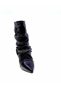 Stivale ankle in pelle nera con un design morbido, punta affusolata e catena decorativa in argento attorno alla caviglia. Texture liscia.