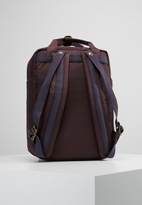 Dark purple backpack featuring adjustable straps, a textured exterior, and metal accents. Compact design with side pocket and sturdy construction.