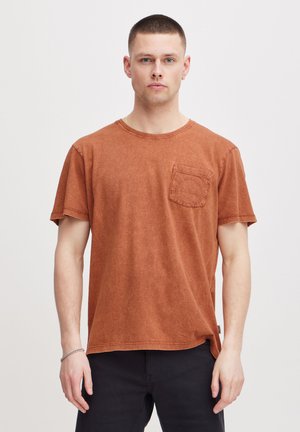 Rust-colored cotton t-shirt with short sleeves, crew neck, and a front pocket. Features a relaxed fit and subtle texture.