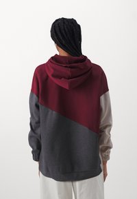 Sudadera con capucha que presenta un diseño a bloques de color con paneles en burdeos, gris y beige. Confeccionada en un tejido suave con puños y dobladillo elásticos.