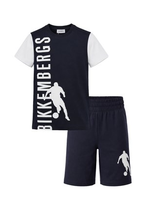 Set di maglietta a maniche corte e pantaloncini blu navy e bianco con silhouette bianca di un calciatore e logo Bikkembergs verticale sulla maglietta.