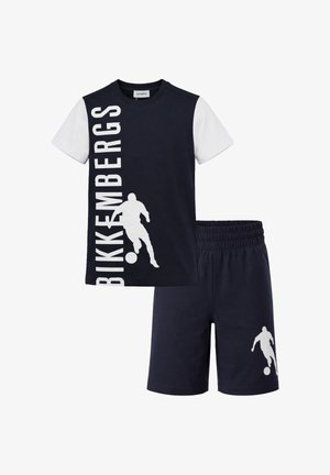Set di maglietta a maniche corte e pantaloncini blu navy e bianco con silhouette bianca di un calciatore e logo Bikkembergs verticale sulla maglietta.