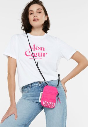 Rosa Nylon Umhängetasche mit schwarzen Akzenten und Logo, ausgestattet mit einem Reißverschlussfach und einem verstellbaren Tragegurt, die um die Taille getragen wird.