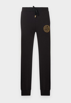 Črne ohlapne tekaške hlače s prirezanim pasom na vrvico in zlatim vejico Versace Jeans Couture na zgornjem levem stegneniču.