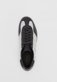 Fekete-fehér sneaker hálós és bőr anyagból, párnázott nyelvvel, fekete fűzőkkel és három fehér csíkkal az oldalon.