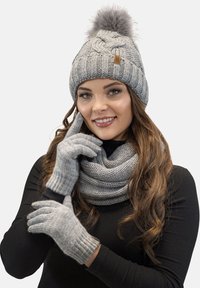 Grijze gebreide beanie met een bontpompon, bijpassende handschoenen en een gestructureerde sjaal. Alle items hebben een zachte, warme textuur en geribbelde accenten.