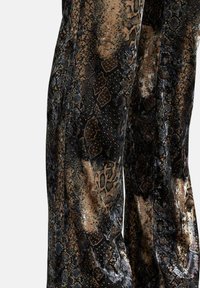Pantaloni in tessuto effetto serpente con finitura lucida, tonalità scure con accenti dorati e marroni, e un design affusolato e aderente.