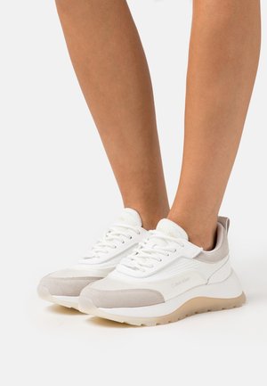 Witte en beige sneakers met een combinatie van leer en mesh, een afgeronde neus, vetersluiting en gestructureerde accenten op het bovenwerk.