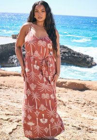 Maximekko, jonka väri on ruosteenpunainen ja jossa on valkoisia palmupuun kuvioita, säädettävät spagettiolkaimet ja sidottu vyötärö, joka luo vartalonmyötäisen siluetin.