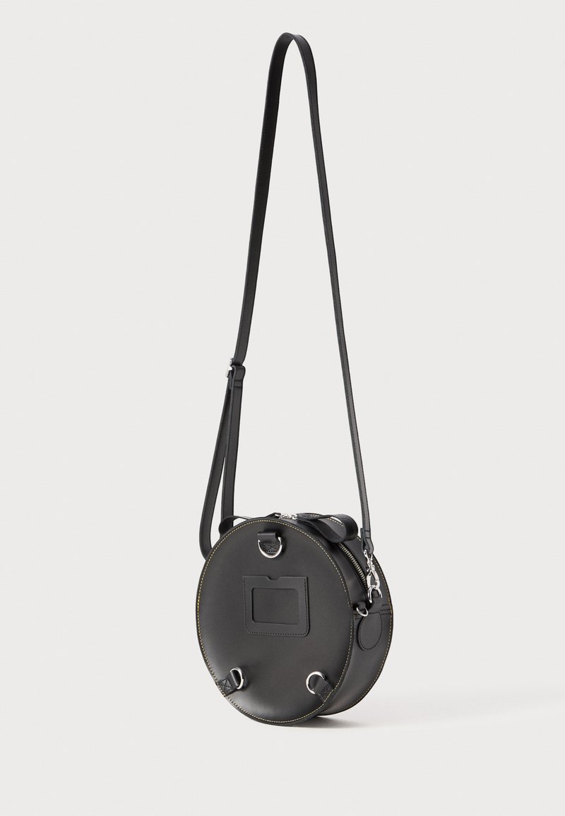 Borsa rotonda in pelle nera con chiusura a zip, tracolla regolabile e dettagli in metallo argentato. Presenta cuciture gialle a contrasto e uno slot per schede.