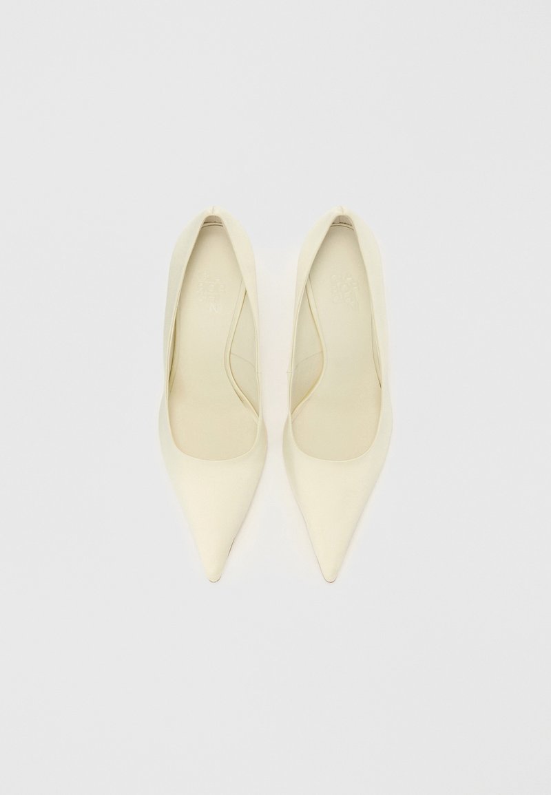 Spitze High Heels aus cremefarbenem synthetischem Material mit glatter Oberfläche. Schlankes, minimalistisches Design ohne sichtbare Verzierungen.