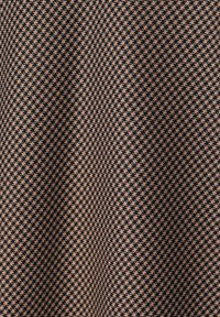 Geometrikus mintázatú textil, váltakozó fekete és bézs árnyalatokban, szoros kötésű és sima textúrájú.