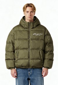 Giacca a piumino verde oliva con cappuccio, design trapuntato orizzontale, chiusura con zip e testo ricamato bianco sul petto sinistro. Polsini rinforzati.