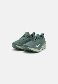 Nike tenisice za trčanje s teksturiranim zelenim gornjim dijelom, svijetlozelenim potplatom i bijelim logotipom. Imaju podstavljeni ovratnik i vezivanje na vezice.