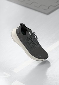 Sportovní obuv v tmavě šedé síťovině, s bledě šedou podrážkou a tkaničkami. Výrazné branding Puma na boku a jazyku. Texturovaný povrch.