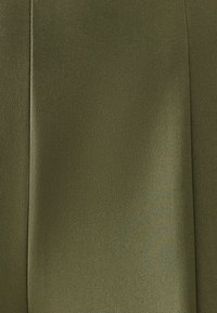 Olivgrüner Stoff mit glatter Textur, der einen dezenten Glanz und ein gefaltetes Design zeigt, was ein sauberes, stromlinienförmiges Erscheinungsbild erzeugt.