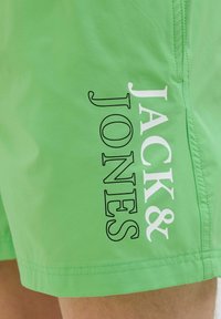 Zelene kupaćice od laganog materijala, s odvažnim crno-bijelim printom "JACK & JONES" na boku i vidljivim šavnim detaljima.