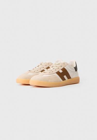 Zapatillas de ante beige con acentos de cuero marrón, punta redonda, paneles laterales blancos y suela de goma. Diseño minimalista con cordones.