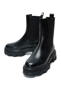 Bottines en cuir noir avec des panneaux élastiques sur les côtés, semelles en caoutchouc épaisses et une boucle à l'arrière pour un enfilage facile. Texture lisse et design robuste.