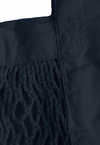 Námorná taška s pevným horným dielom a sieťovaným dolným dielom, vyrobená z odolných materiálov s textúrovaným povrchom.