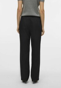 Sorte videbukser med en glat tekstur, der har en høj talje og en skræddersyet pasform, vist fra bagsiden.