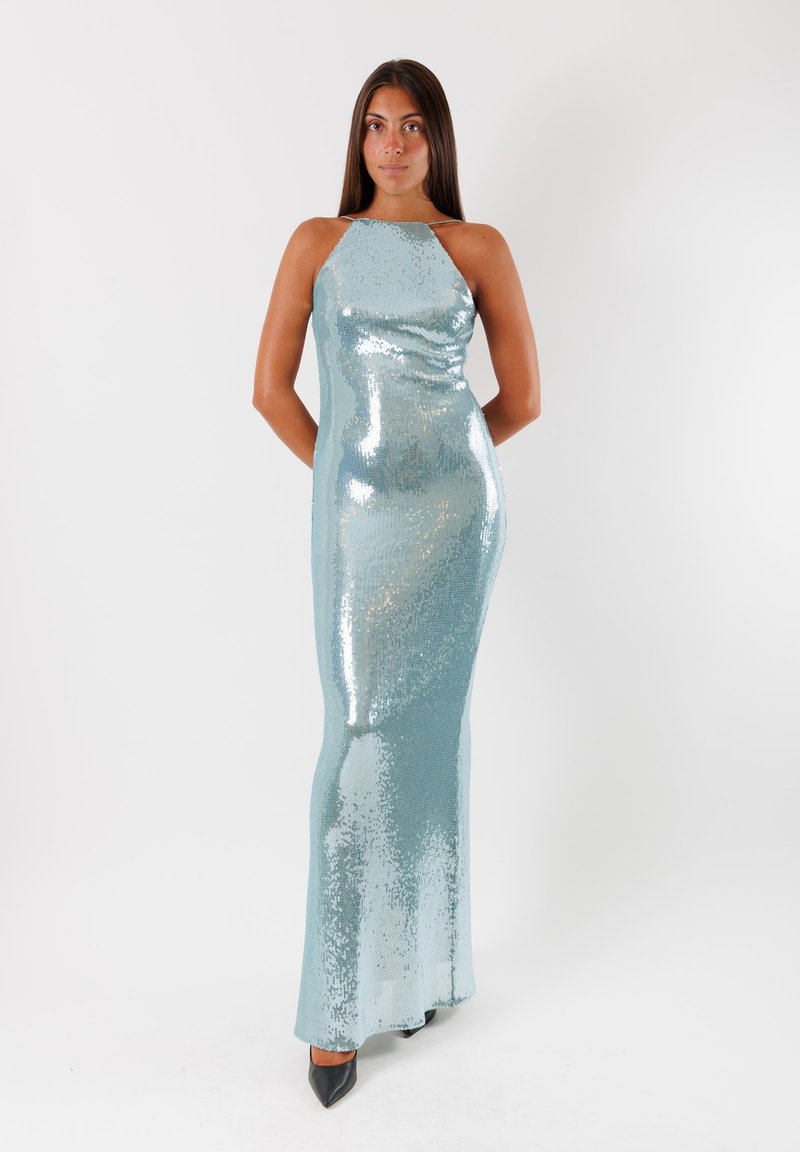 Abito da sera in paillettes di colore azzurro chiaro con silhouette aderente. Presenta un collo all'americana e scende fino a terra. Tacchi neri a punta completano il look.
